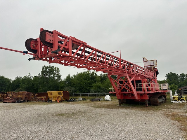 Side view of a red Sandvik D90KS rotary blast hole drill with its drill mast lowered horizontally.