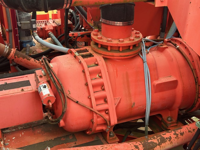 Close-up of the engine and hydraulic components of a red Sandvik mining machine.