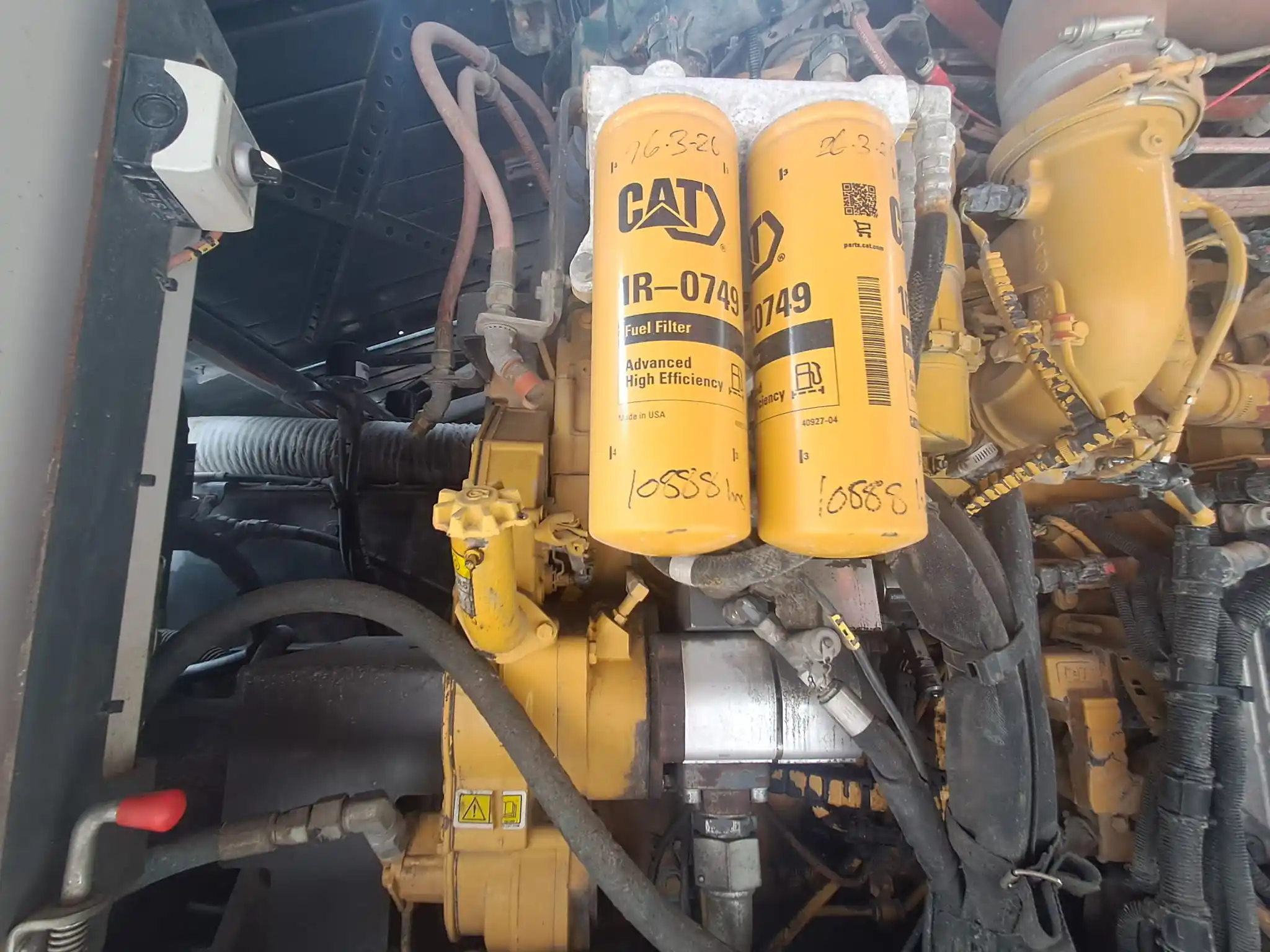 Two CAT fuel filters mounted inside a machinery engine compartment.